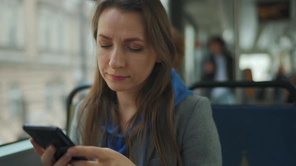 Woman in Tram Using Smartphone Chatting and Texting with Friends