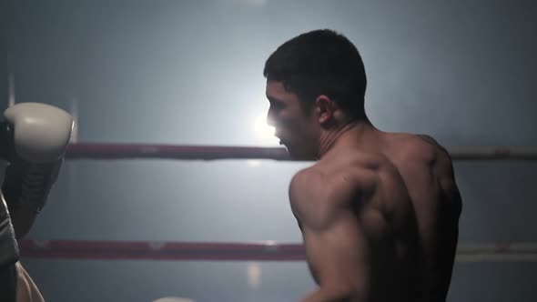 Cinematic Slow Motion Shot of Two Professional Young Muscular Shirtless Male Boxers Fighting in a