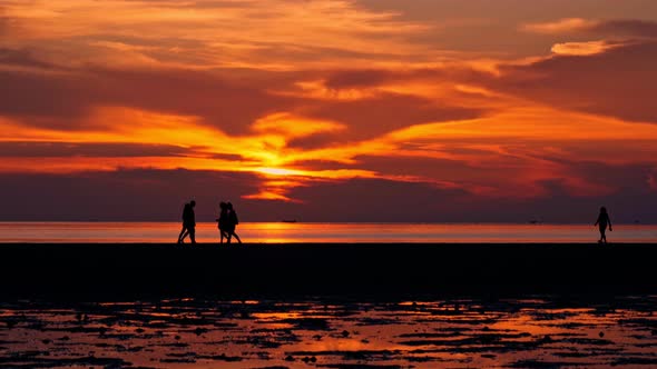 People Walking By the Beach at Sunset