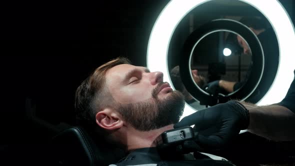 Barber Shaves the Client's Beard on a Chair. Beard Haircut. Barber To Shave a Beard with an Electric