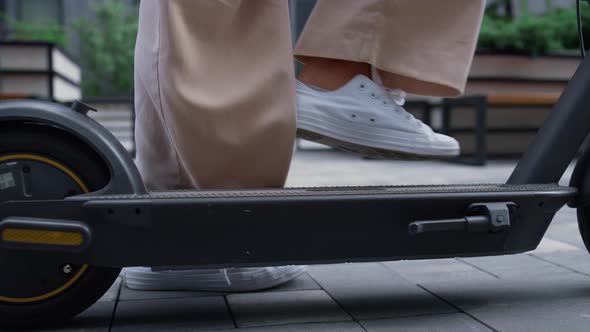 Woman Legs Riding Kickscooter in White Sneakers Going Away at Downtown Closeup