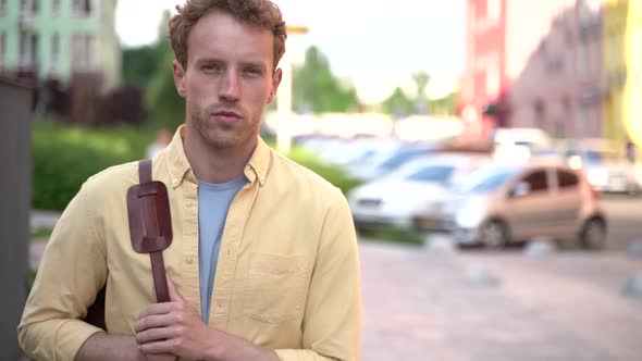 Serious, young man with a bag on his shoulder walks down an empty street