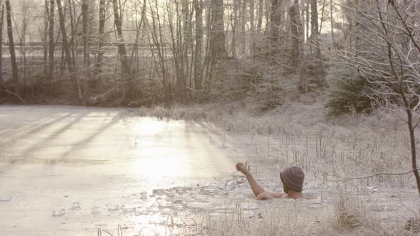 Stunning BACKLIT shot of an ice bather climbing out of his ice hole