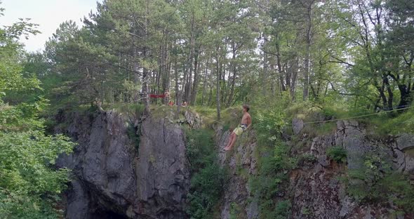 A man swinging while slacklining on a tightrope in the mountains.