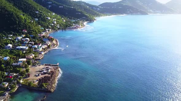 Aerial British Virgin Island Tortola beach fly by of local homes on the water angle 2