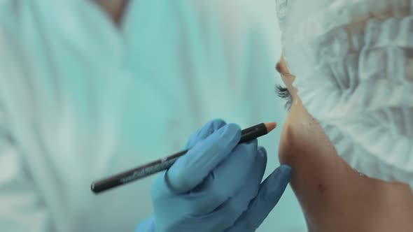 The Beautician in the Office Marks the Client's Face with a Pencil Closeup