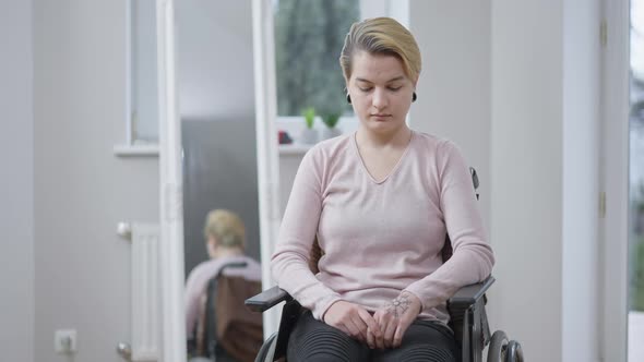 Portrait of Young Stressed Paraplegic Woman Sitting on Wheelchair Looking at Camera and Praying