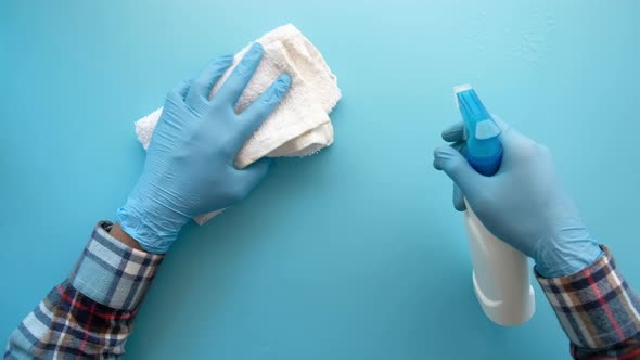 Hand in Blue Rubber Gloves Holding Spray Bottle