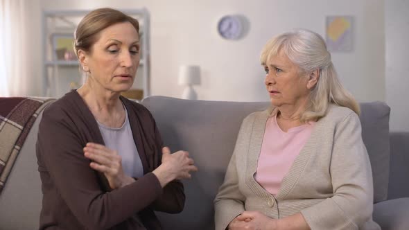 Self-Assertive Old Women Arguing and Offending Each Other Sitting in Living Room
