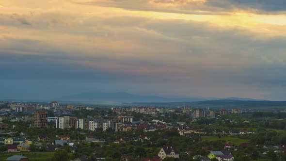 Time lapse footage of fast moving evening clouds on yellow sky over rural city area with distant