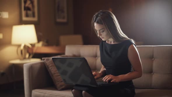 Young Female Working at a Laptop Woman Sitting on the Couch in the Hotel Business Trip