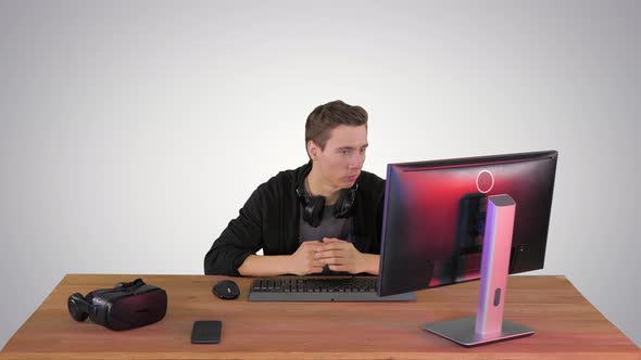Serious Gamer Sitting at Computer Watching a Game on Gradient Background.