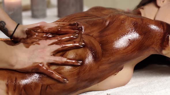 Close-up of Masseur Arms Massaging Body with Chocolate