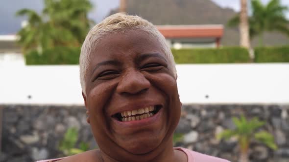 Happy Latin mature woman having fun smiling in front of camera on house patio