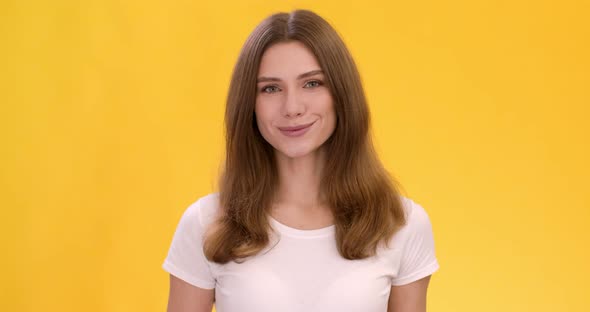 Studio Portrait of Young Cute Caucasian Woman Smiling Over Orange Background