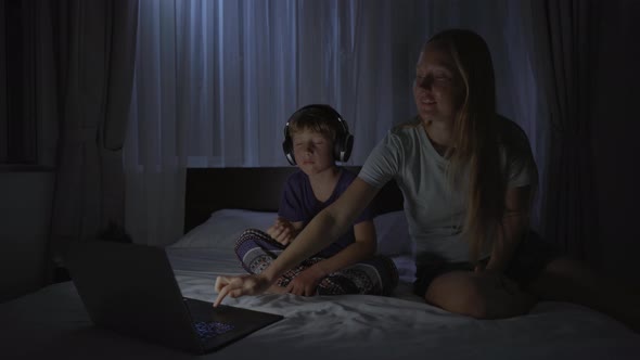 A Woman at Night Turns on a Meditation Relaxation Application on Her Computer for Her Son to Relax