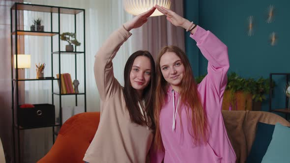 Happy Girls Siblings Making Roof Gesture Sign of Hands New Home Ownership Insurance Bank Loan