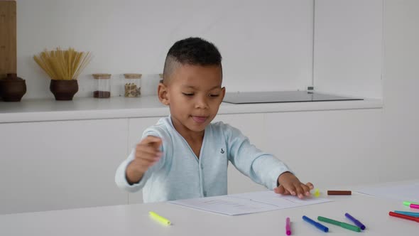 Funny Little African American Boy Drawing With Colorful Pencils At Home