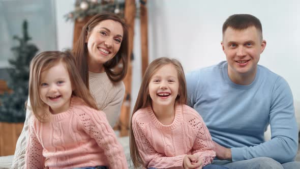 Attractive Family Posing with Christmas Decoration at Home Laughing Looking at Camera