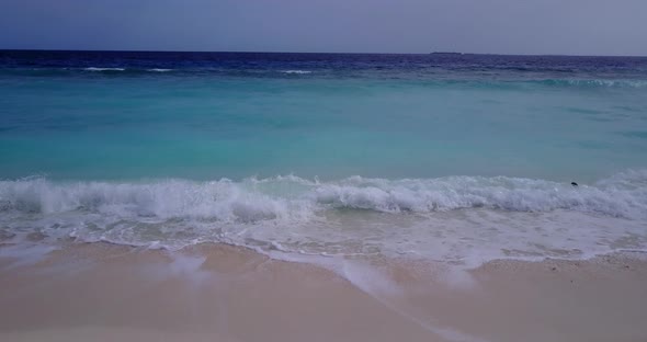 Natural fly over tourism shot of a sandy white paradise beach and aqua blue water background in high