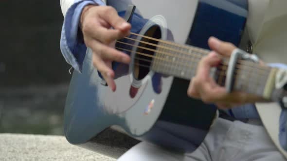 Close-up detail of a man playing guitar hands.