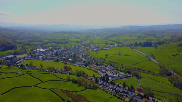An aerial view from a drone flying over  lush green hills towards the  old rural village of Staveley