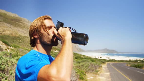 Triathlete man drinking water in the countryside road