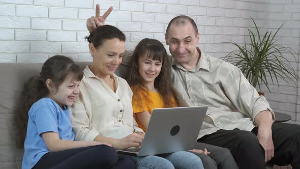 Cheerful Family Communicates on a Laptop