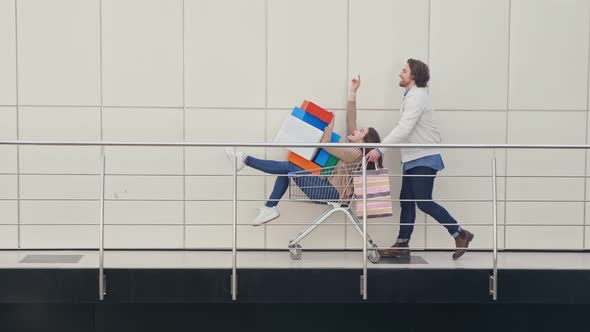 A Man Pushing a Shopping Cart With a Woman Holding Shopping Bags and Gifts for Christmas