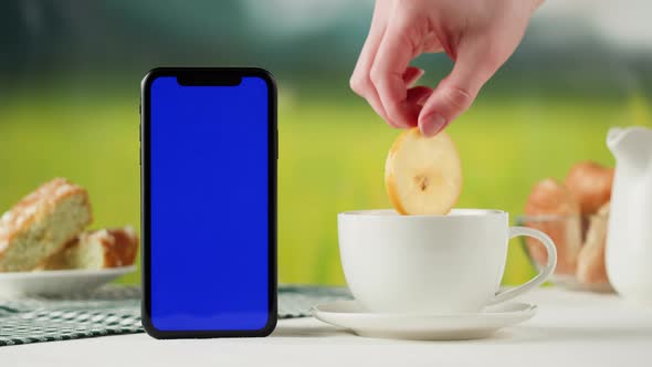 Smartphone with Blue Chroma Key Screen and Tea Cup Closeup