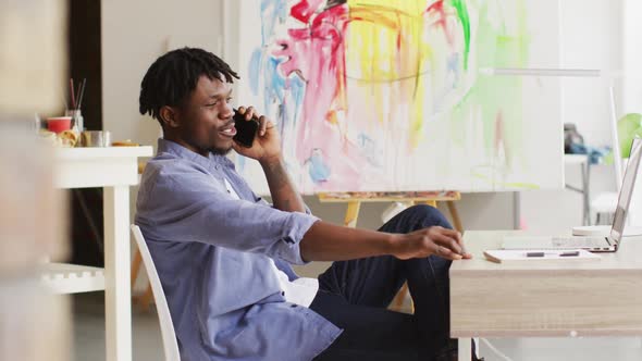 African american male artist talking on smartphone at art studio