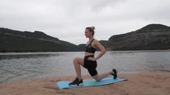 Fit women stretching her left leg next to a lake