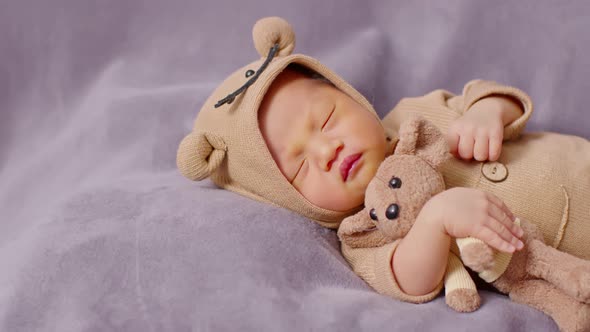 happy newborn baby weaing cute Mouse costume lying sleeps and hug doll on Beige background