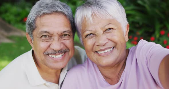 Video of happy biracial senior couple taking selfie in garden