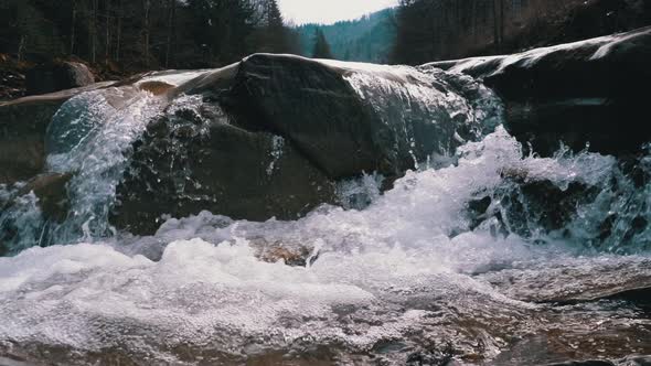 Mountain Creek and Stone Rapids with Snow. Rapid Flow of Water. Waterfall in the Winter. Slow Motion