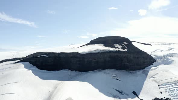 Aerial view overlooking a mountain and snowmobile on the Langjokull glacier, in Iceland - rising, dr