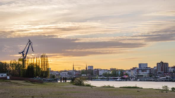 Hamburg Germany, river Elbe on south coast during sunset looking into sun disappearing behind silhou alt