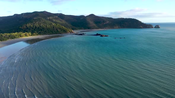 Cape Hillsborough aerial tracking backwards with turquoise ocean waves, Mackay Queensland