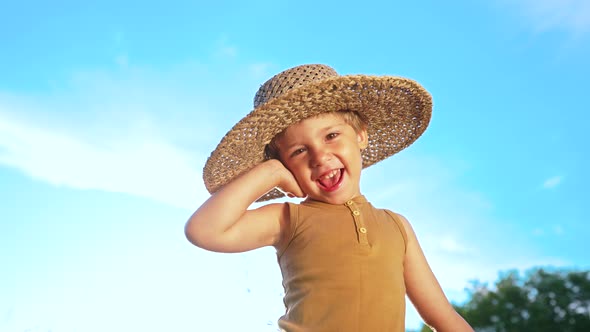 Adorable Smiling Boy in Straw Hat on Blue Sky Background