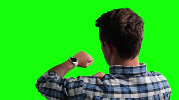 a Caucasian man checking his smartwatch in a green background