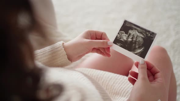 Top View of a Woman's Pregnant Belly and a Photo of an Ultrasound of a Baby