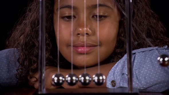 Girl Playing With A Newton's Cradle