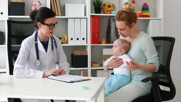 Doctor Pediatrician and Mother with Baby Patient in Clinic