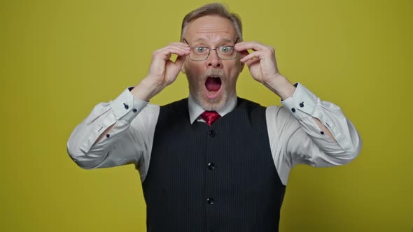 Funny mature man with glasses. Surprised male in elegant clothing putting on glasses.