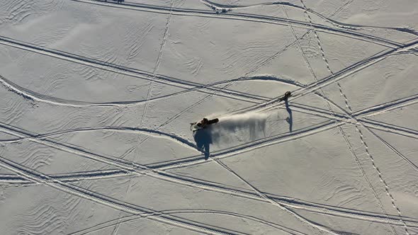 Birdseye Drone Aerial View of Snowmobile and Skier, Winter Snow Fun and Activity on Sunny Day
