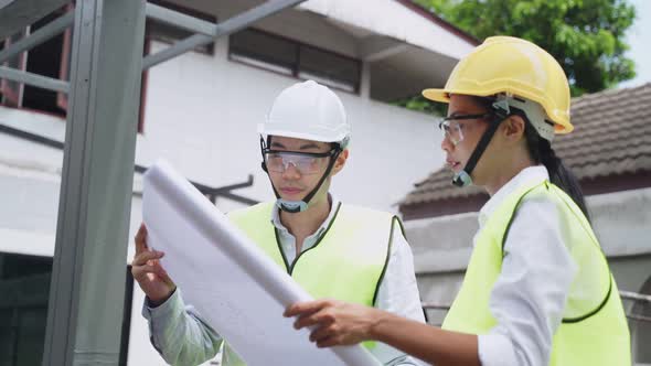 Asian construction workers and builder people holding drawing and working onsite of architecture.