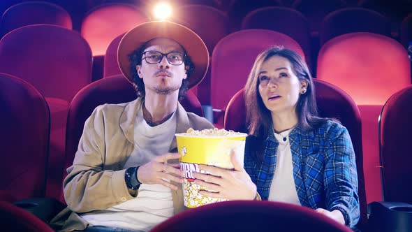 A Man and a Woman are Eating Popcorn While Watching a Movie