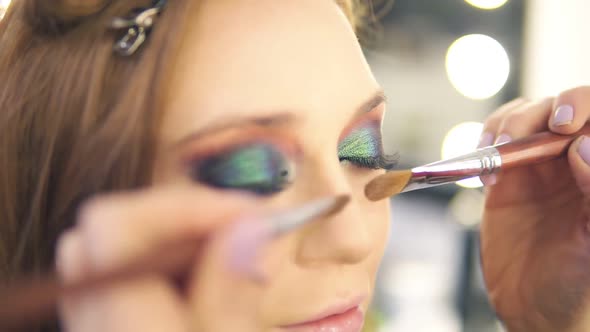 Makeup Artist Structuring Nose of the Young Woman Using Foundation and Two Brushes