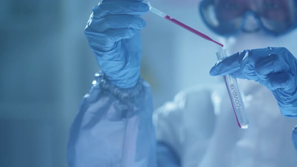 Lab Scientist Pouring Blood into Test Tube with Covid-19 Inscription