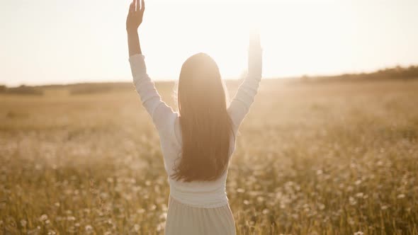 A Happy Woman is Jumping Raising Her Hands on Field at Sunset